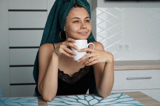 Beautiful woman in a towel on hair with a cup of coffee