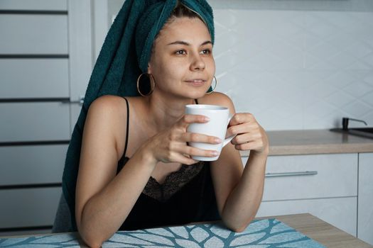 Beautiful woman in a towel on hair with a cup of coffee