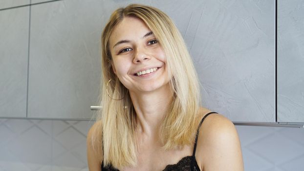 Cheerful young female smiling and looking at camera in cozy styled kitchen
