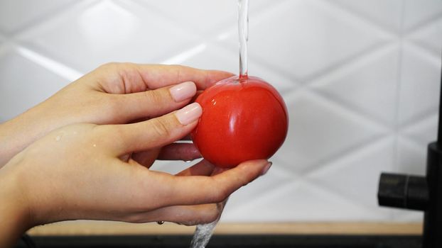 Woman washing tomatoes and tomato in her hands - white kitchen background