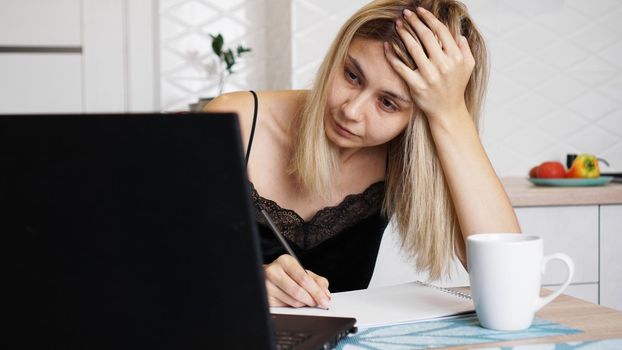 A businesswoman works at home or homeschooling a student using her laptop. Woman holding her head and worried about the problem