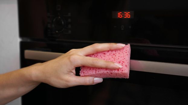 Cleaning the oven outside. A female hand cleans oven panel. Girl polishing kitchen.