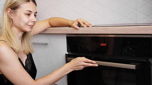 Young woman cooking in the kitchen opening the oven door