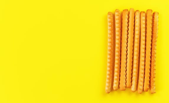 Grissini, also known as breadsticks on yellow board, view from above space for text left side.