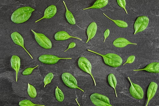 Corn salad Valerianella locusta leaves arranged in pattern over black slate like board - overhead shot. Healthy green leaf food concept.