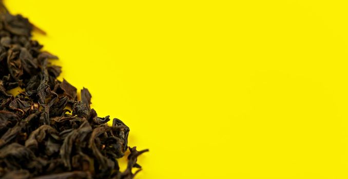 Loose black tea Assam variety on yellow board, view from above space for text right side.