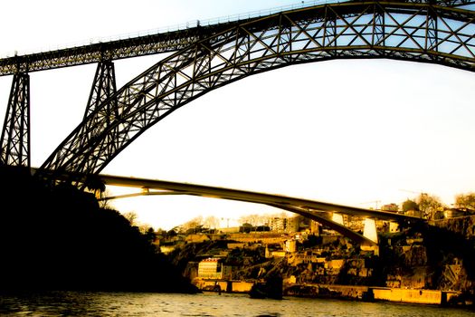 Beautiful and colossal iron bridges called Maria Pia and Ponte do Infante over the waters of the Douro River in Porto at sunset