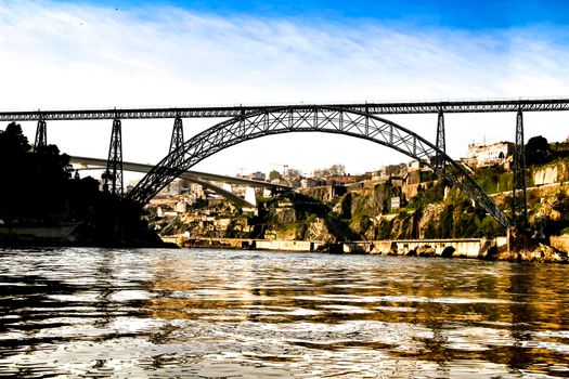 Beautiful and colossal iron bridges called Maria Pia and Ponte do Infante over the waters of the Douro River in Porto at sunset