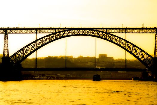 Beautiful and colossal iron bridge called Dom Luis I over the waters of the Douro River in Porto at sunset