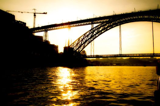 Beautiful and colossal iron bridge called Dom Luis I over the waters of the Douro River in Porto at sunset