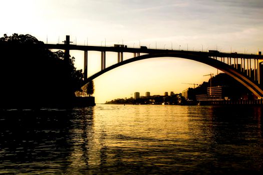 Beautiful and colossal iron bridge called Dom Luis I over the waters of the Douro River in Porto at sunset
