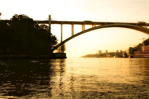 Beautiful and colossal iron bridge called Dom Luis I over the waters of the Douro River in Porto at sunset