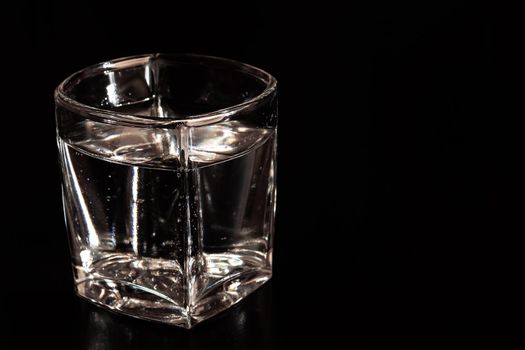 Glass with mineral water with bubbles on a black background