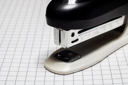 Stapler on the page of a notebook in a cage closeup