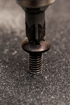 Screwdriver twists the screw close up, macro photo, copy space