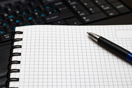 Writing book and pen on a laptop background close up