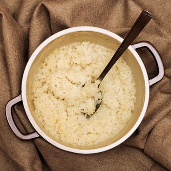 Rice porridge and spoon in a pan on a cloth of burlap