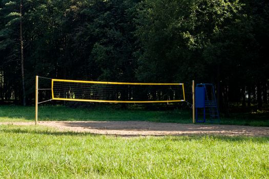 Volleyball net in the sand in the park among the trees