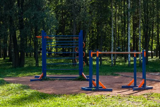Fitness equipment in the park among the trees in summer