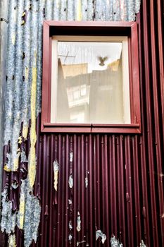 Old house facade with rusty balcony and green blind in Cordoba, Spain.