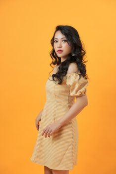 Portrait of a beautiful girl in a light summer dress. Isolated over yellow background.