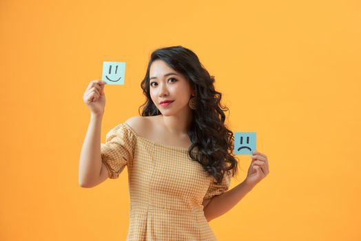 Photo of funny lady holding paper emoticons good and bad mood picking positive emotions