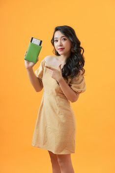 Beautiful portrait young asian woman smile confident holding and pointing passport with travel summer trip in vacation