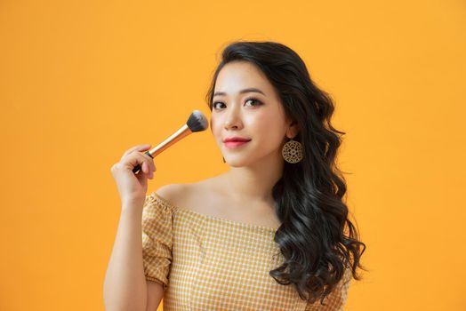 Portrait of attractive young Asian woman with beautiful skin holding brush for make up.