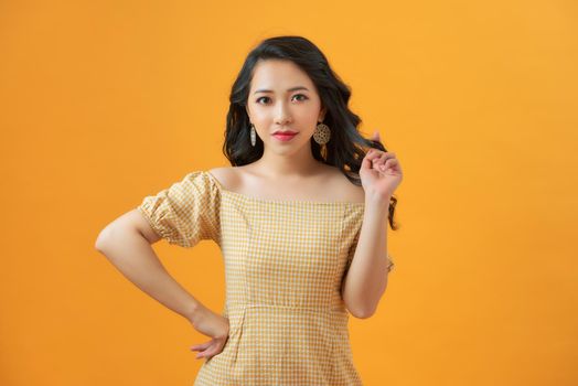 Excited Fashion Girl. Smiling beautiful woman in mini dress posing against yellow background.