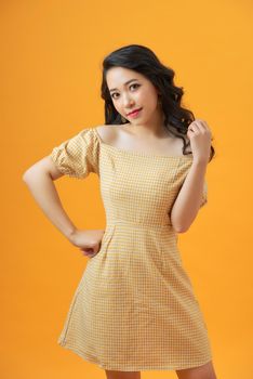 fashion portrait of attractive smiling young woman in yellow dress on yellow studio background, elegant style, summer trend