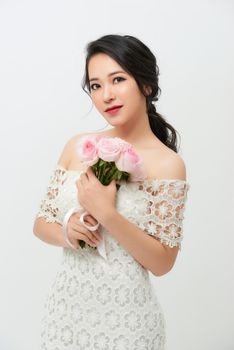 Gorgeous young bride with a rose bouquet isolated against white background.