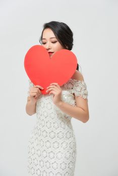 Full body studio portrait of a young casual woman holding red heart and looking up