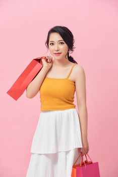 beautiful young woman with colored shopping bags over pink background