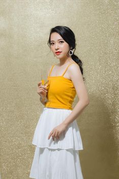 Young attractive young woman holding champagne wine over gold background. Party, holiday, Christmas, New Year concept