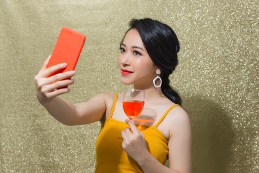 Party time. Beautiful young Asian woman making selfie on the phone in "party" glasses.