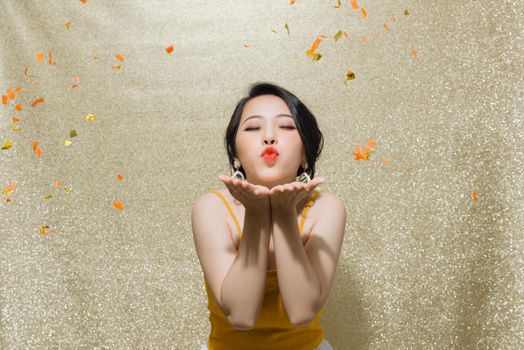 Portrait of beautiful young woman with party whistle and falling confetti on color background