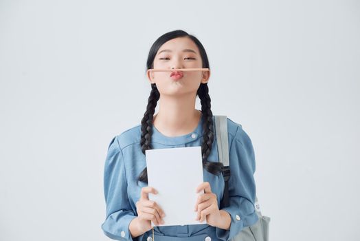 Funny asian woman with notebooks holding pencil with lips, positive lifestyle