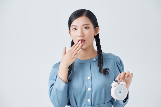 Young teenager Asian girl over isolated white background holding vintage alarm clock