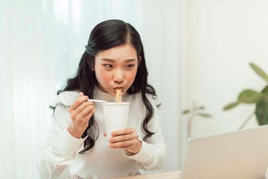 Asian business woman eating noodle at office desk for lunch time