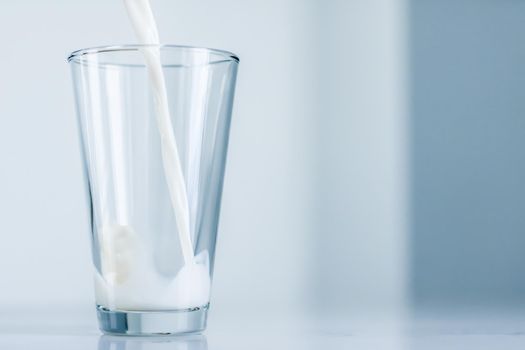 Dairy, healthy nutrition and breakfast concept - World Milk Day, pouring into glass on marble table