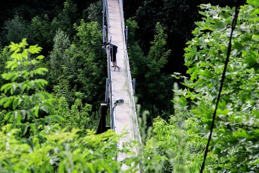 Two people on a wooden bridge over the precipice in summer