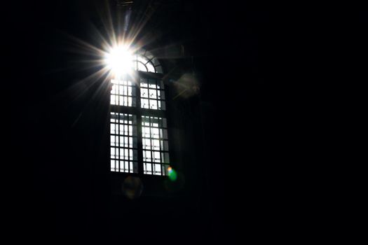 The bright rays of the sun in the window in a dark room, copy space