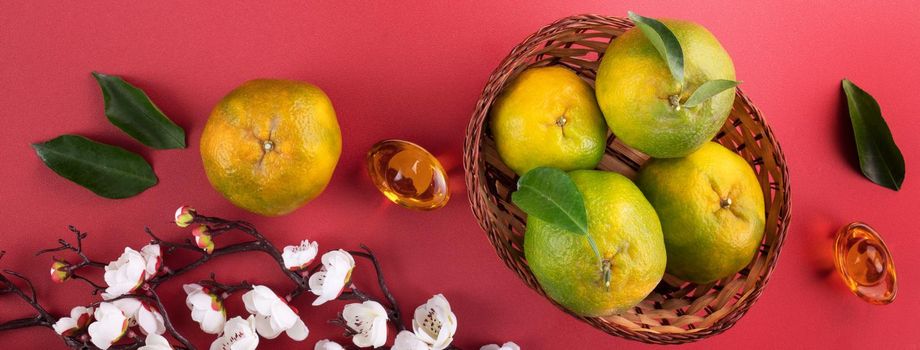 Top view of fresh ripe tangerine mandarin orange with fresh leaves on red table background for Chinese lunar new year fruit concept, the Chinese word means spring.