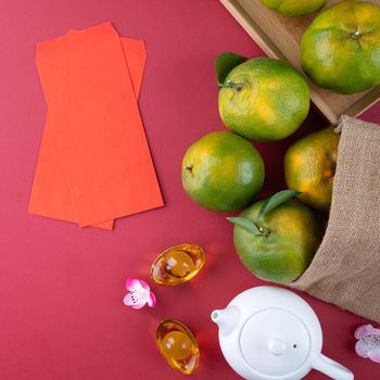 Top view of fresh ripe tangerine mandarin orange with fresh leaves on red table background for Chinese lunar new year fruit concept, the Chinese word means spring.