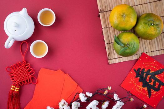 Top view of fresh ripe tangerine mandarin orange with fresh leaves on red table background for Chinese lunar new year fruit concept, the Chinese word means spring.