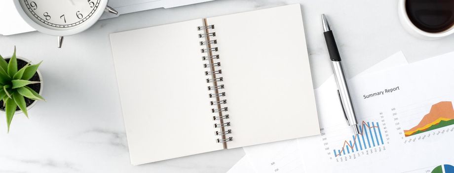Top view of office table desk work concept with blank notebook, report, alarm clock on marble white background, concept of timing management and schedule planning.