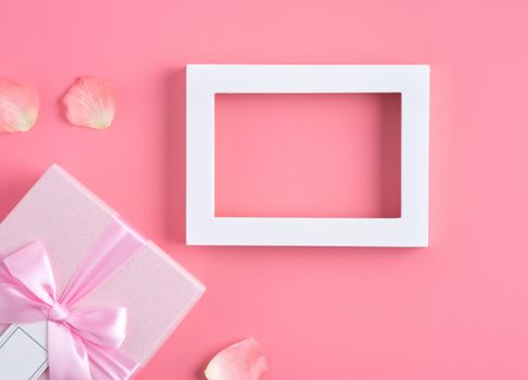 Valentine's Day design concept background with pink petals and gift box on pink background