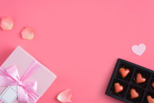 Valentine's Day design concept background with pink petals and gift box on pink background