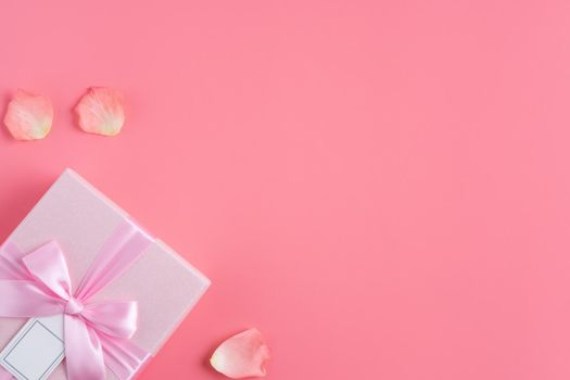 Valentine's Day design concept background with pink petals and gift box on pink background
