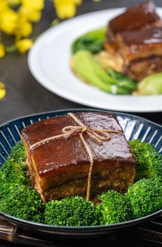 Dong Po Rou (Dongpo pork meat) in a beautiful blue plate with green broccoli vegetable, traditional festive food for Chinese new year cuisine meal, close up.